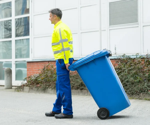 Happy Male Worker Walking With Dustbin On Street During Day